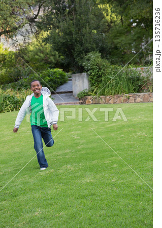African American child running toward camera on lawn in zip-up jacket and jeans, copy space African American child running toward camera on lawn in zip-up jacket and jeans, copy space 135716236