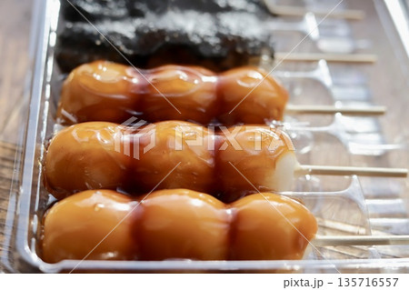 プラスチックケースに入れてある串団子　みたらし団子と胡麻団子 135716557