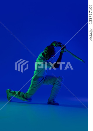 Cricket batsman dramatic defensive shot under blue studio light. Cricket batsman dramatic defensive shot under blue studio light. 135717106