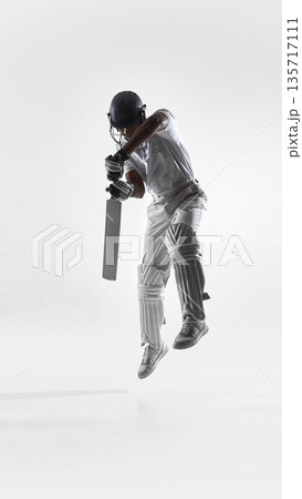 Cricket batsman airborne downward shot in studio isolated on white. 135717111