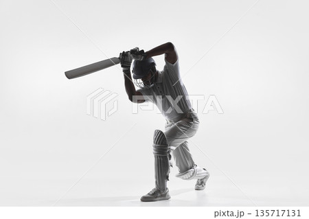Cricket player powerful overhead bat swing in studio isolated on white. 135717131