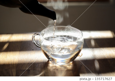 鉄瓶で沸かしてガラスカップに注いでいる白湯 鉄瓶で沸かしてガラスカップに注いでいる白湯 135717627