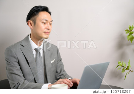 カフェで仕事をするスーツの男性 135718297
