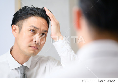 鏡で髪を気にする男性 135718422