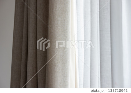 A closeup of layered beige and white curtains 135718941