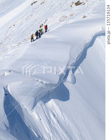 厳冬期の谷川岳・巨大な雪庇の横を通過する登山者 135719134