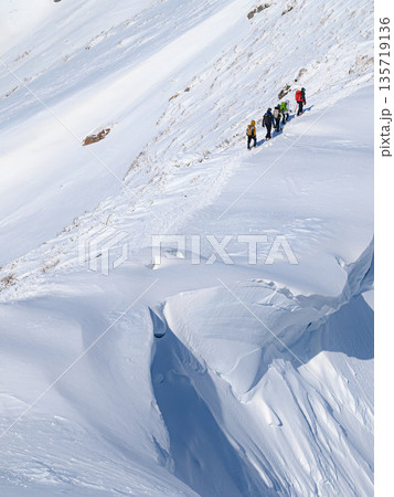厳冬期の谷川岳・巨大な雪庇の横を通過する登山者 厳冬期の谷川岳・巨大な雪庇の横を通過する登山者 135719136