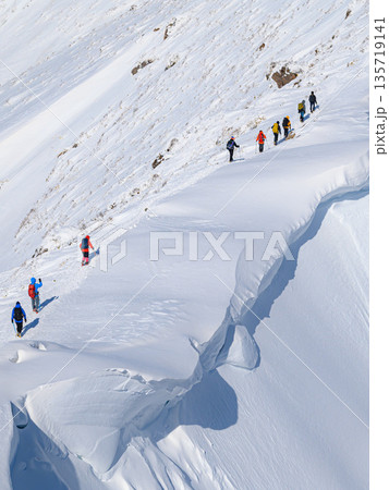 厳冬期の谷川岳・巨大な雪庇の横を通過する登山者 135719141