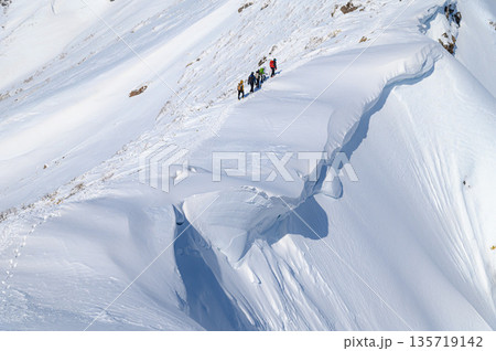 厳冬期の谷川岳・巨大な雪庇の横を通過する登山者 厳冬期の谷川岳・巨大な雪庇の横を通過する登山者 135719142