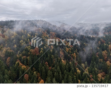 autumn hues under overcast mountain skies, dramatic scene with foggy ridges and vibrant autumn colors 135719417