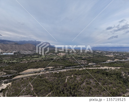 expansive scenic vista, vast landscape with cloudy skies, broad valley view beneath stormy clouds and hills 135719525