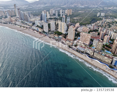 seaside neighborhood with sandy shoreline, aerial perspective showcasing tranquil coast and urban backdrop 135719538