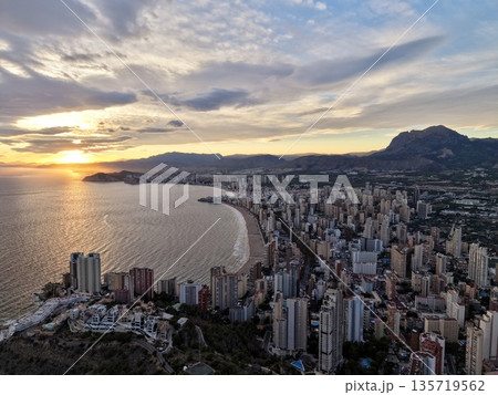 evening cityscape glow, warm evening horizon reflecting across tranquil seaside vistas and vibrant clouds 135719562