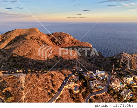 scenic aerial of hillside settlement, drone shot depicting luminous houses on rocky hillside slopes scenic aerial of hillside settlement, drone shot depicting luminous houses on rocky hillside slopes 135719568