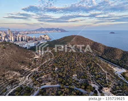 drone shot of city from peaceful heights, calm sea views with mountain trails and urban backdrop drone shot of city from peaceful heights, calm sea views with mountain trails and urban backdrop 135719625