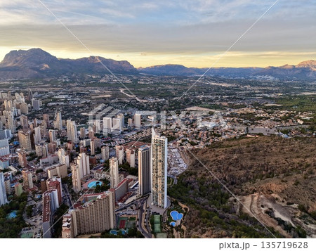 expansive seaside city blending with hills, aerial perspective of busy coast and surrounding hillsides 135719628