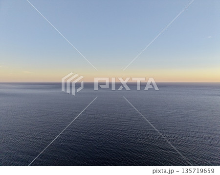 peaceful early morning ocean scene, calm ocean at sunrise with soft colors and reflective surface 135719659