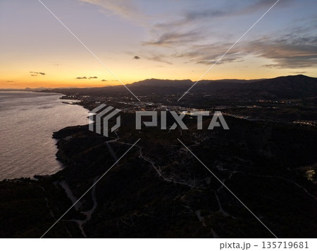 serene dusk sky over beach town with shimmering waters and mountain silhouettes in distance serene dusk sky over beach town with shimmering waters and mountain silhouettes in distance 135719681