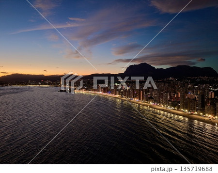 twilight above city highlighting shimmering water reflections and towering structures with vivid sky twilight above city highlighting shimmering water reflections and towering structures with vivid sky 135719688
