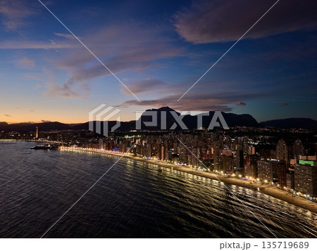 majestic mountain crest overlooking peaceful bay illuminated by shimmering urban and sky reflections majestic mountain crest overlooking peaceful bay illuminated by shimmering urban and sky reflections 135719689