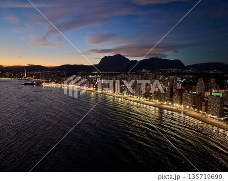spectacular cityscape highlighting illuminated beachfront and bustling nightlife against mountain scenery spectacular cityscape highlighting illuminated beachfront and bustling nightlife against mountain scenery 135719690