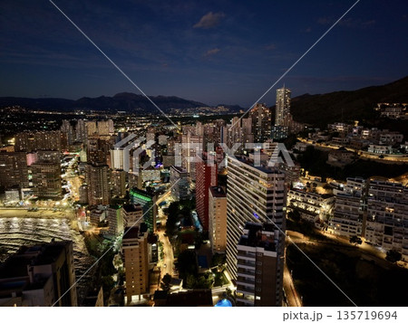 serene sunset over waterfront urban area, calm dusk horizon with twinkling lights and distant mountains serene sunset over waterfront urban area, calm dusk horizon with twinkling lights and distant mountains 135719694