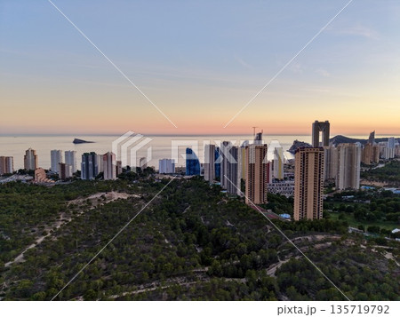 twilight cityscape near ocean, evening cityscape with illuminated towers and peaceful waterscape twilight cityscape near ocean, evening cityscape with illuminated towers and peaceful waterscape 135719792