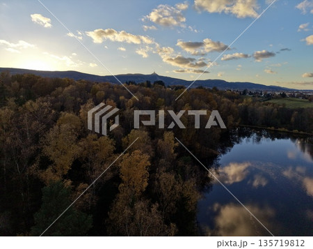 aerial perspective of peaceful lakeside scene at twilight with colorful foliage and distant mountains aerial perspective of peaceful lakeside scene at twilight with colorful foliage and distant mountains 135719812