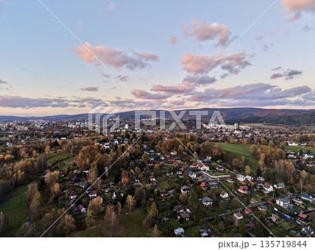 gentle dusk panorama capturing cozy settlement surrounded by rolling hills and soothing light 135719844