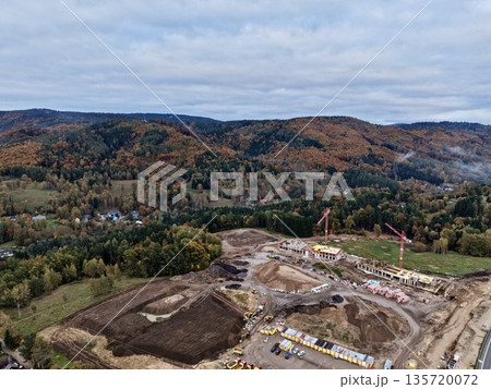 industrial site with cranes and earthworks, autumn hillside construction with machinery and surveying industrial site with cranes and earthworks, autumn hillside construction with machinery and surveying 135720072