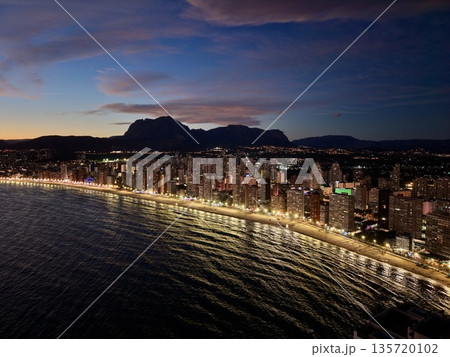 vibrant beach nightlife, bustling coastal metropolis illuminated by colorful evening illuminations 135720102