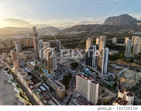 bright sunset over elegant waterfront towers, golden hour illuminates upscale skyscrapers near mountains 135720110