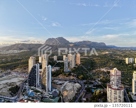 sunrise mountain view, elevated perspective captures peaceful shoreline and towering structures at dawn 135720111