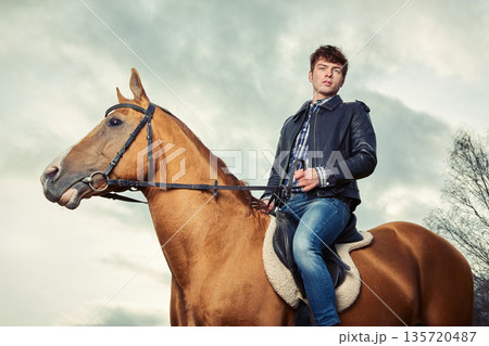 A man riding a horse outdoors 135720487