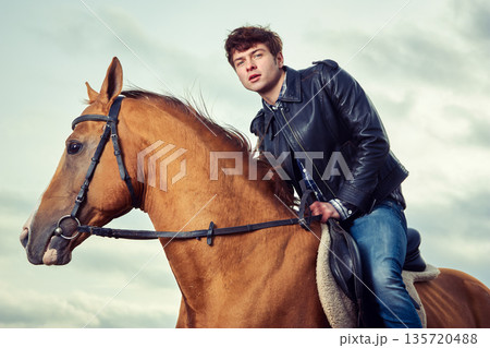A man riding a horse outdoors 135720488