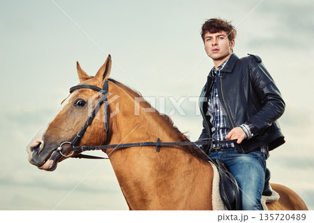 A man riding a horse outdoors 135720489