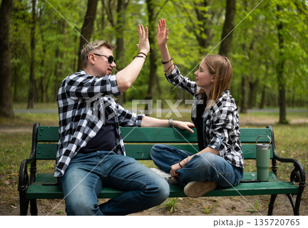 Happy Father And Little Daughter Sit On A Bench Giving A High Five In Family Look 135720765