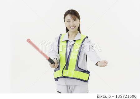 白背景の作業服の安全ベルトをつけて誘導灯を持つ若い日本人女性 白背景の作業服の安全ベルトをつけて誘導灯を持つ若い日本人女性 135721600