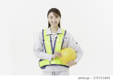 白背景の作業服の安全ベルトをつけてヘルメットを持つ若い日本人女性 白背景の作業服の安全ベルトをつけてヘルメットを持つ若い日本人女性 135721605