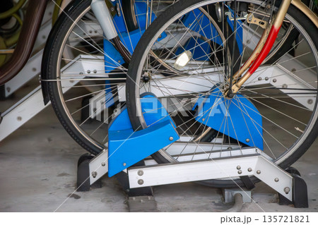 駐輪場の駐輪機に固定される自転車の前輪 135721821