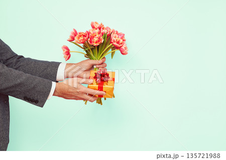 Man presents a gift box and bouquet of tulips Man presents a gift box and bouquet of tulips 135721988