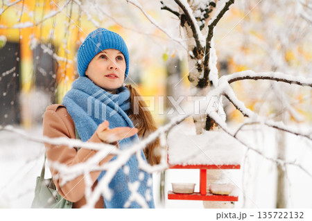 Woman feeding birds in a feeder Woman feeding birds in a feeder 135722132