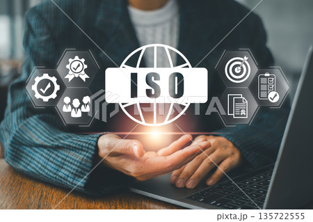 Business Professional Presenting ISO Certification Concept with Digital Icons and Laptop in Modern Office Setting 135722555