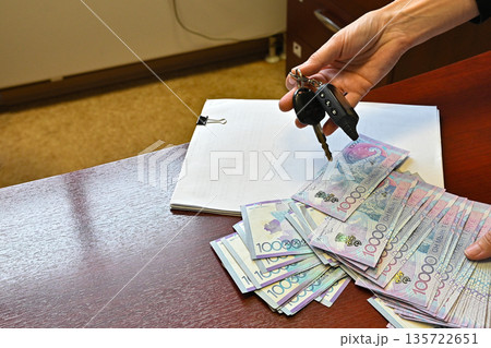 Holding a fan of colorful banknotes in hand during a financial transaction at a local market in the afternoon light 135722651