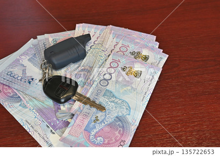 Counting cash on the table, next to the car keys, in the office during the day. Buying a new car. Counting cash on the table, next to the car keys, in the office during the day. Buying a new car. 135722653