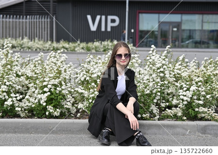 Woman in sunglasses smiling near white flowers on a sunny day outdoors. 135722660