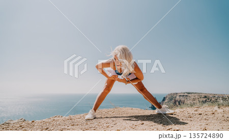 Woman Stretching on Cliffside Overlooking Ocean Woman Stretching on Cliffside Overlooking Ocean 135724890
