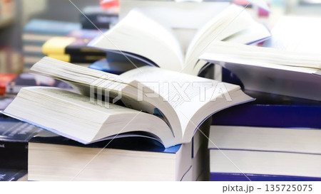 stack of books, close up. Open book on the table in library. Back to school concept. Open book on table with blur bookshelf background 135725075