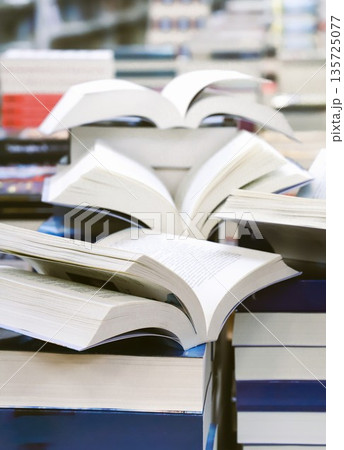 stack of books, close up. Open book on the table in library. Back to school concept. Open book on table with blur bookshelf background stack of books, close up. Open book on the table in library. Back to school concept. Open book on table with blur bookshelf background 135725077