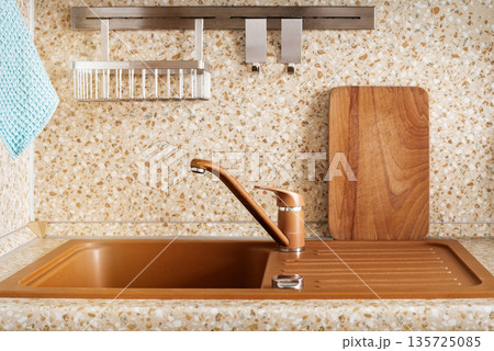Minimal kitchen sink area with wooden cutting board 135725085